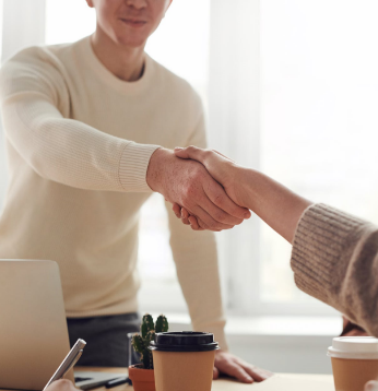 Man in White Sweater Shaking Hands with Person in Gray Sweater